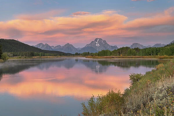 Orange clouds and Mount Moran reflected in still waters of the Snake River at Oxbow Bend at sunrise, Grand Teton National Park, Wyoming. Date: 16-09-2019