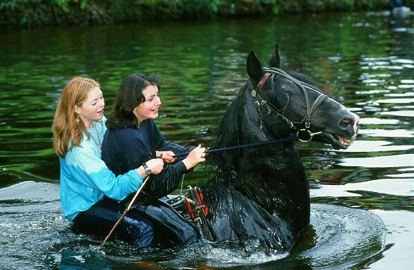 Gypsey girls riding a horse in the River Eden at the Appleby horse Fair Cumbria UK