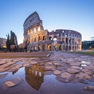 The Colosseum (Flavian Amphitheatre), UNESCO World Heritage Site, reflected in a puddle at dusk