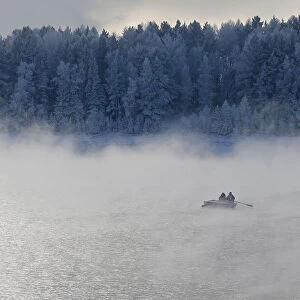 Two men row a boat through a frosty fog along the Yenisei River at air temperature some