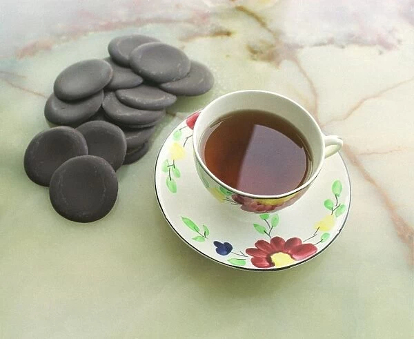 Cup of black tea with chocolate rounds