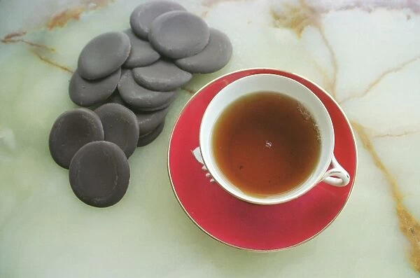 Cup of black tea with chocolate rounds