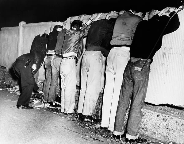 BROOKLYN: GANGS, 1956. Policemen frisking gang members on Pacific Street between
