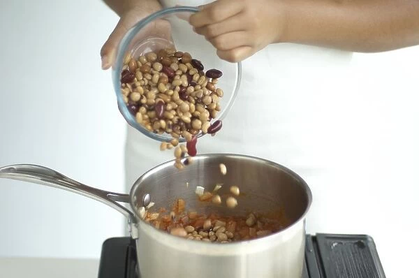Pouring mixed beans into sauce pan containing tomato sauce