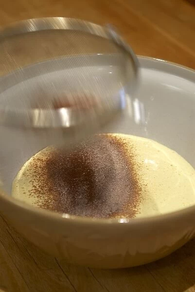 Sifting flour and cocoa into mixture of eggs and sugar