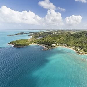 Aerial view of the rugged coast of Antigua full of bays and beaches fringed by dense