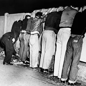 BROOKLYN: GANGS, 1956. Policemen frisking gang members on Pacific Street between