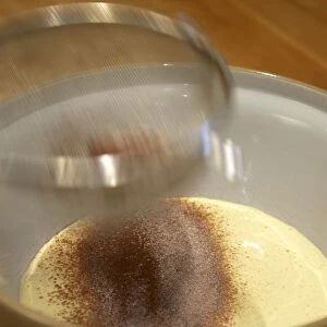 Sifting flour and cocoa into mixture of eggs and sugar